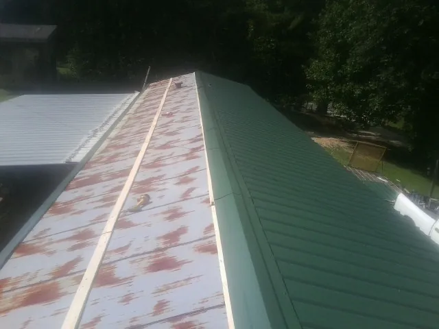 Old rusted panels beside newly installed green metal roofing — Wind Damage Roof Repair by Roofing Brothers in Oak Ridge
