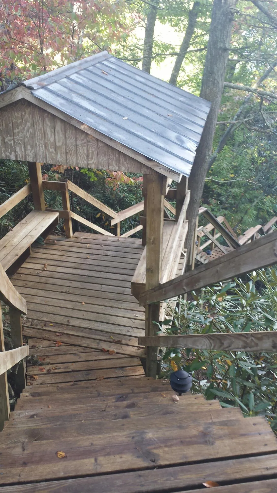 Metal roofed shelter over wooden steps on a wooded walkway — Skylight Repair & Installation work by our crew in Oak Ridge